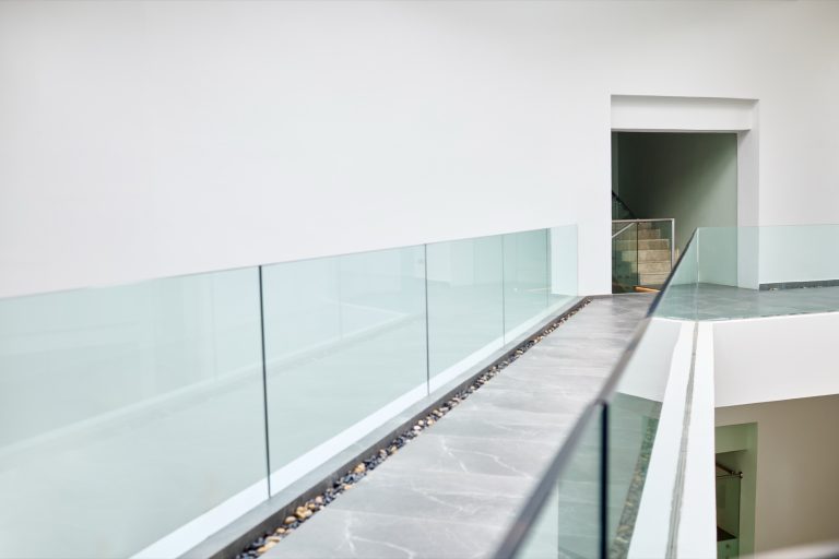 Frameless clear glass balustrade along a bright gallery walkway