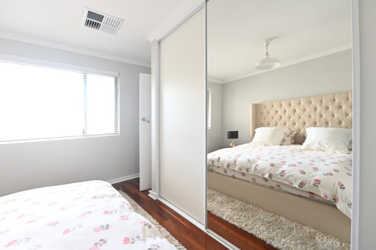 Vinyl backed mirror wardrobe doors reflecting a bedroom